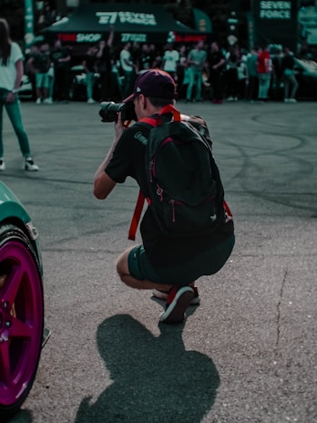 Behind-the-scenes shot of a photographer capturing a car event with a professional camera.