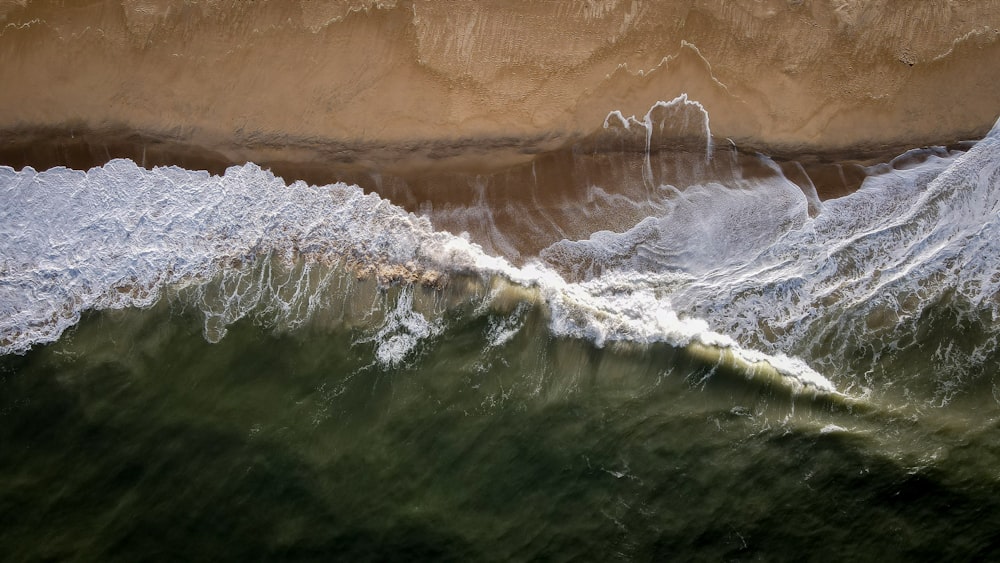 an aerial view of a wave breaking on the beach