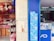 A shop display with an assortment of colorful backpacks and footwear on shelves. The adjacent store features promotional posters for a 20MP Softlight Camera smartphone by Vivo. Inside, there's a clean, modern interior with lit displays.