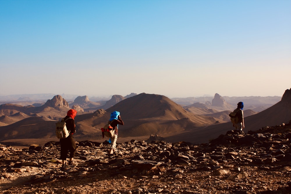 a group of people walking across a rocky hillside