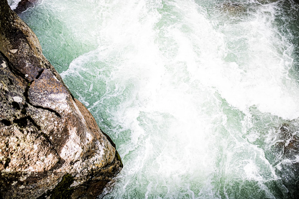 a man standing on top of a rock next to a river