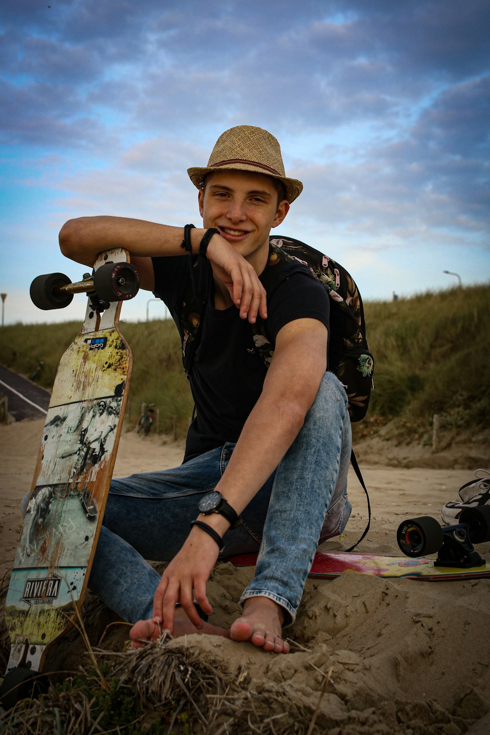 a man sitting in the sand with a skateboard