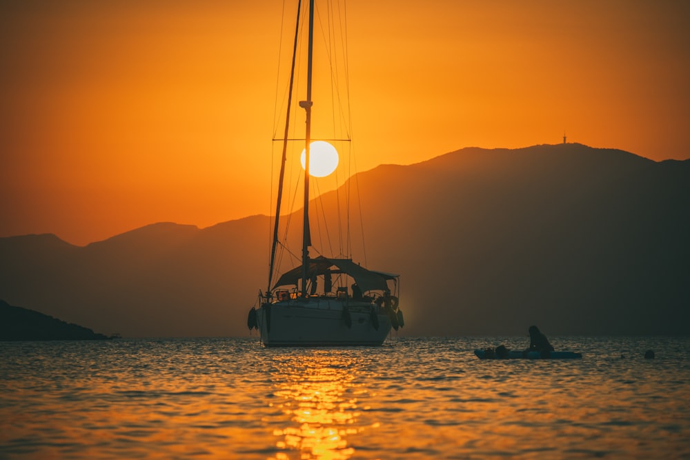 a sailboat in a body of water at sunset