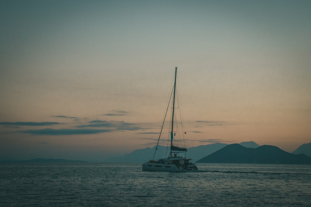 a sailboat in the ocean at sunset