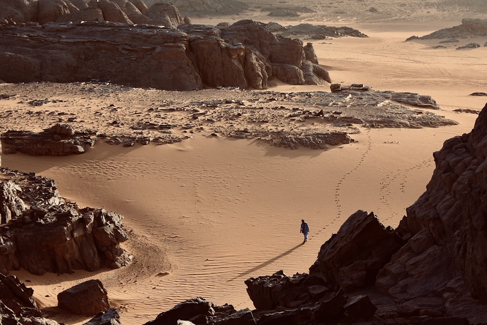 a person walking across a sandy desert area