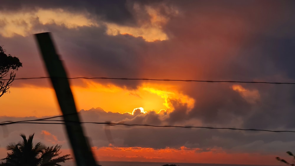 the sun is setting behind a wire fence