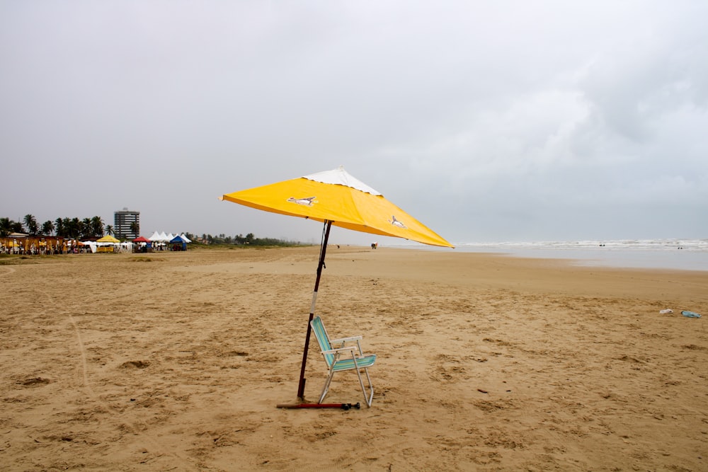 a yellow umbrella and chair on a beach