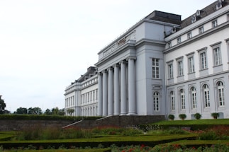 a large white building sitting next to a lush green park