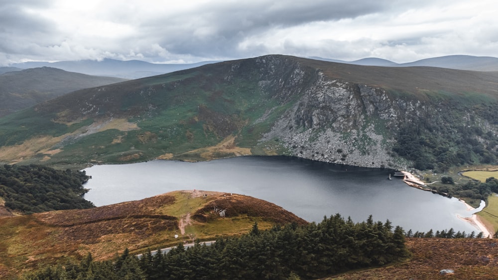 a lake surrounded by mountains under a cloudy sky