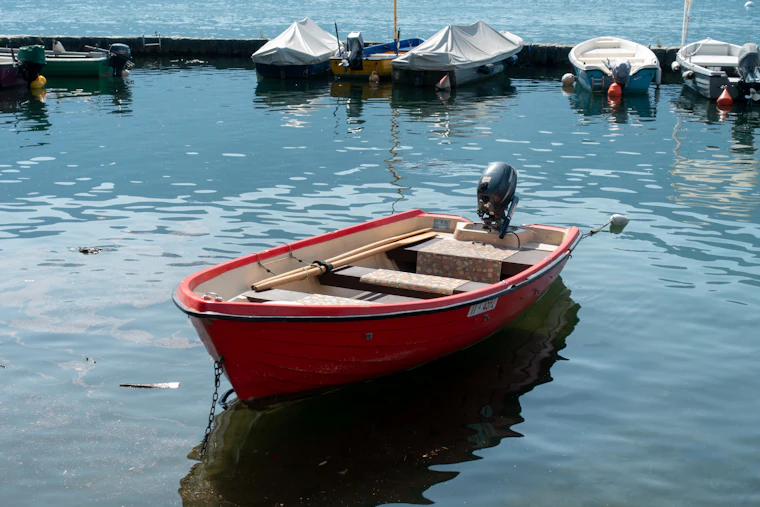 A small red fishing boat moored on flat calm water