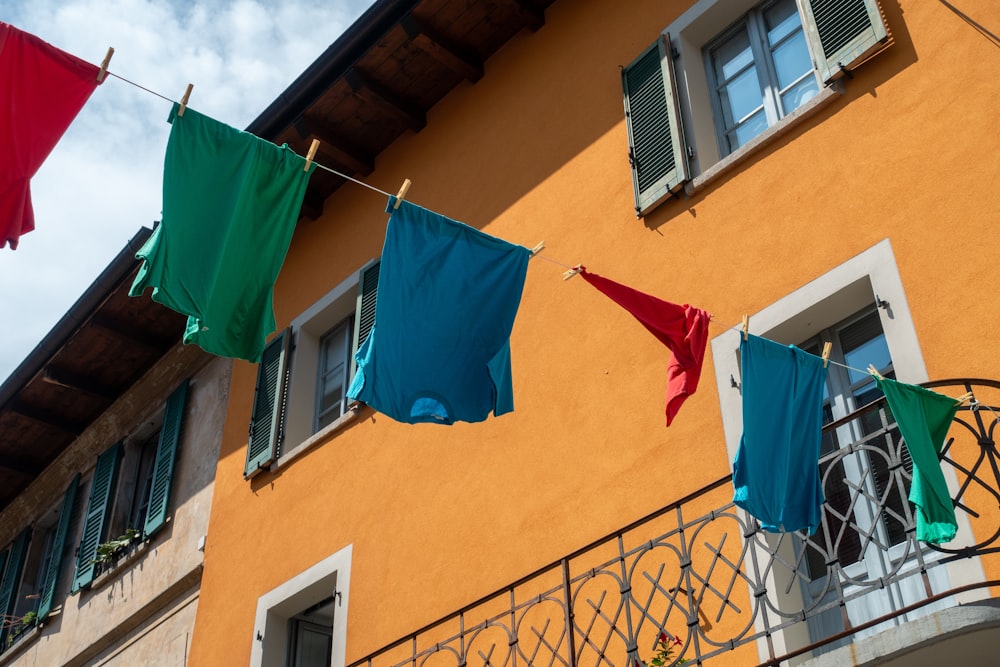 bunte Kleidung hängt an einer Wäscheleine vor einem Gebäude