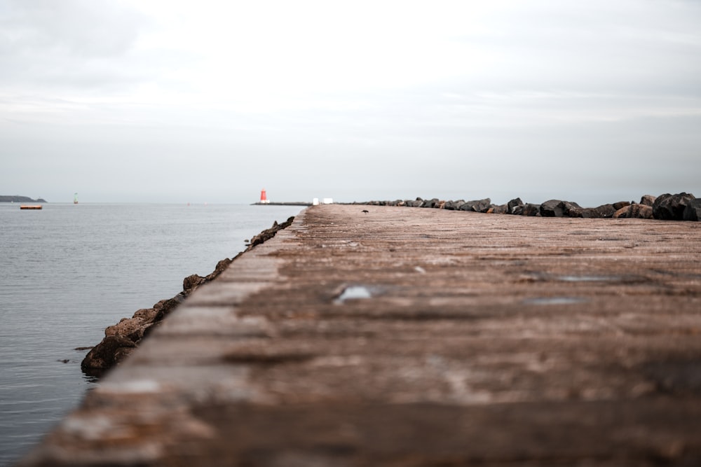 a long pier with a light house in the distance