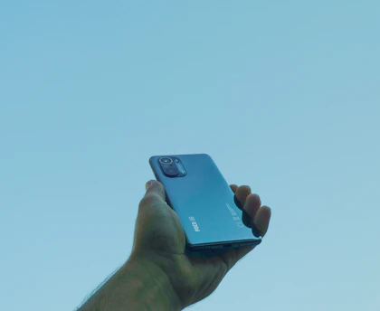 A hand holding a modern phone with a clean, minimalistic AI app screen in bright daylight.