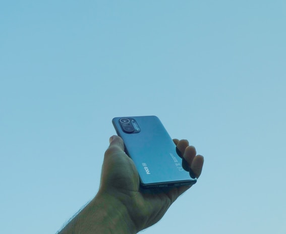 Close-up of hands holding a smartphone displaying a clean, minimal real estate app interface.
