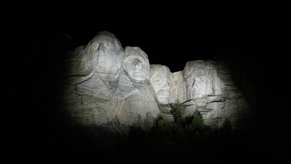 a group of carved faces on a rock formation