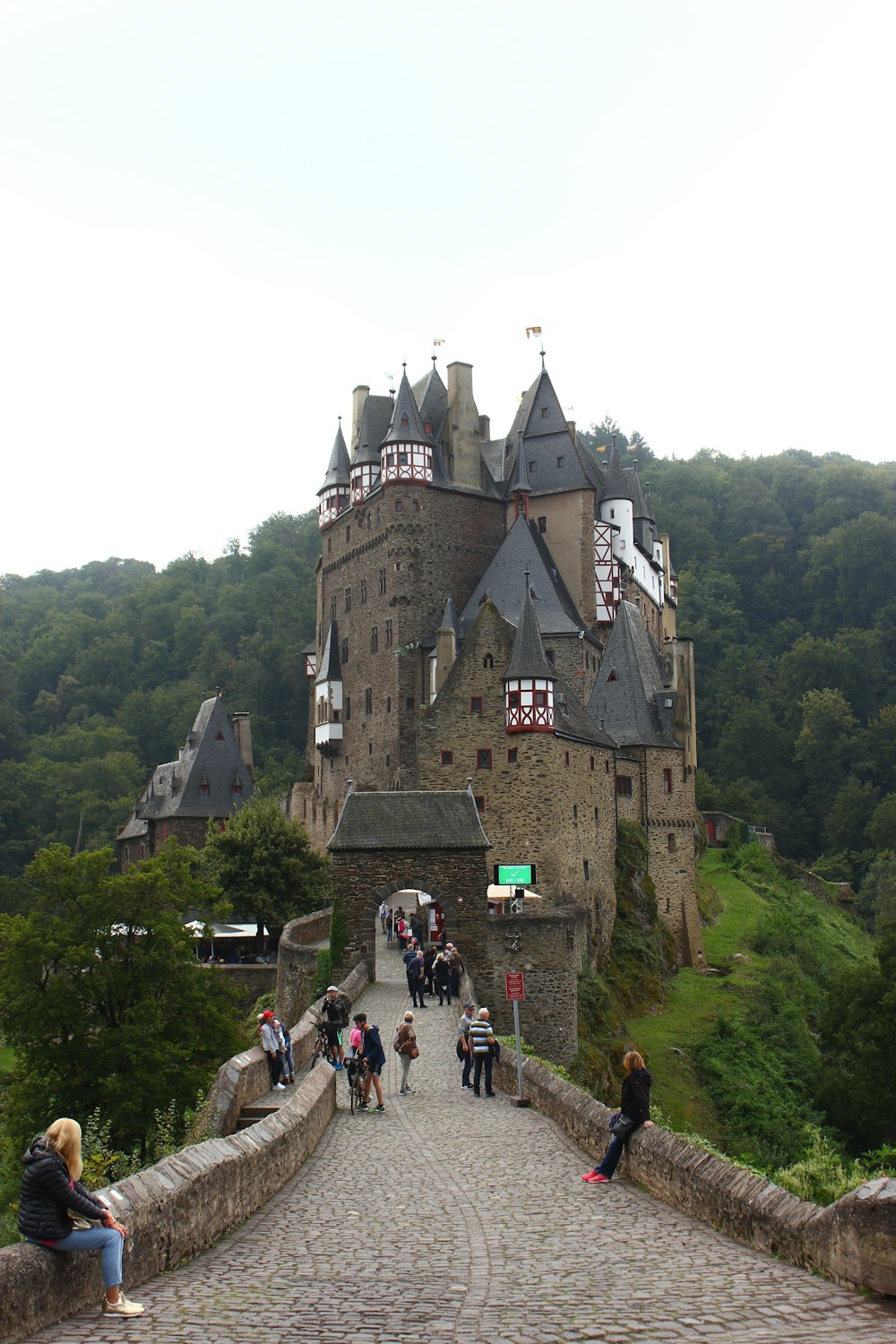 a group of people sitting on a stone bridge in front of a castle