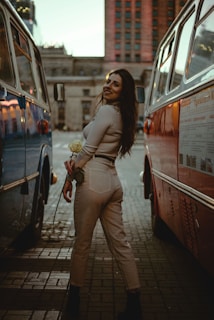 a woman standing next to a bus on a street