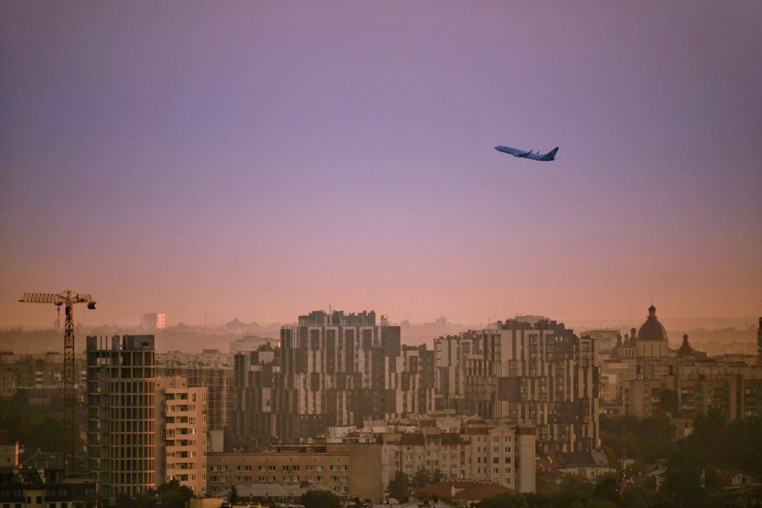 an airplane flying over a city with tall buildings, Early departure from Lviv
