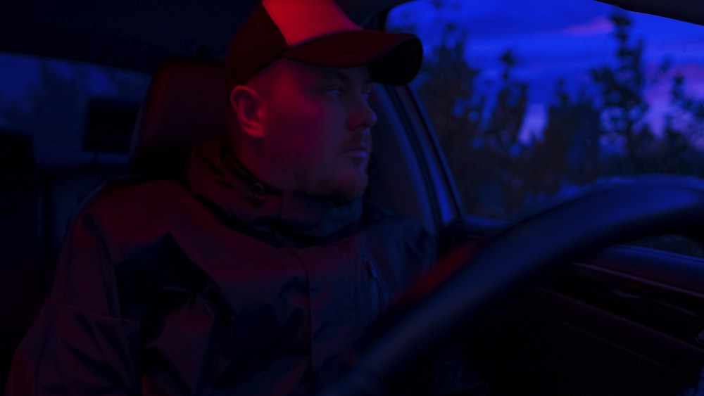 a man sitting in a car with a red hat on