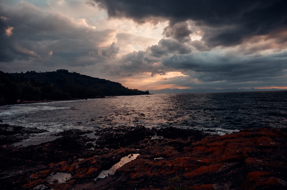 the sun is setting over the ocean on a cloudy day