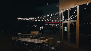 Outdoor seating area at dusk illuminated by multiple metal wall sconces, creating a warm inviting atmosphere