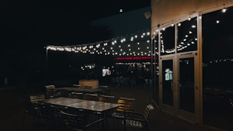 Outdoor seating area at dusk illuminated by multiple metal wall sconces, creating a warm inviting atmosphere