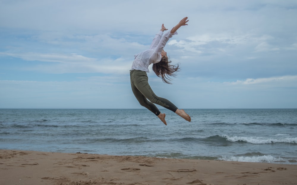 해변에서 공중으로 점프하는 여자