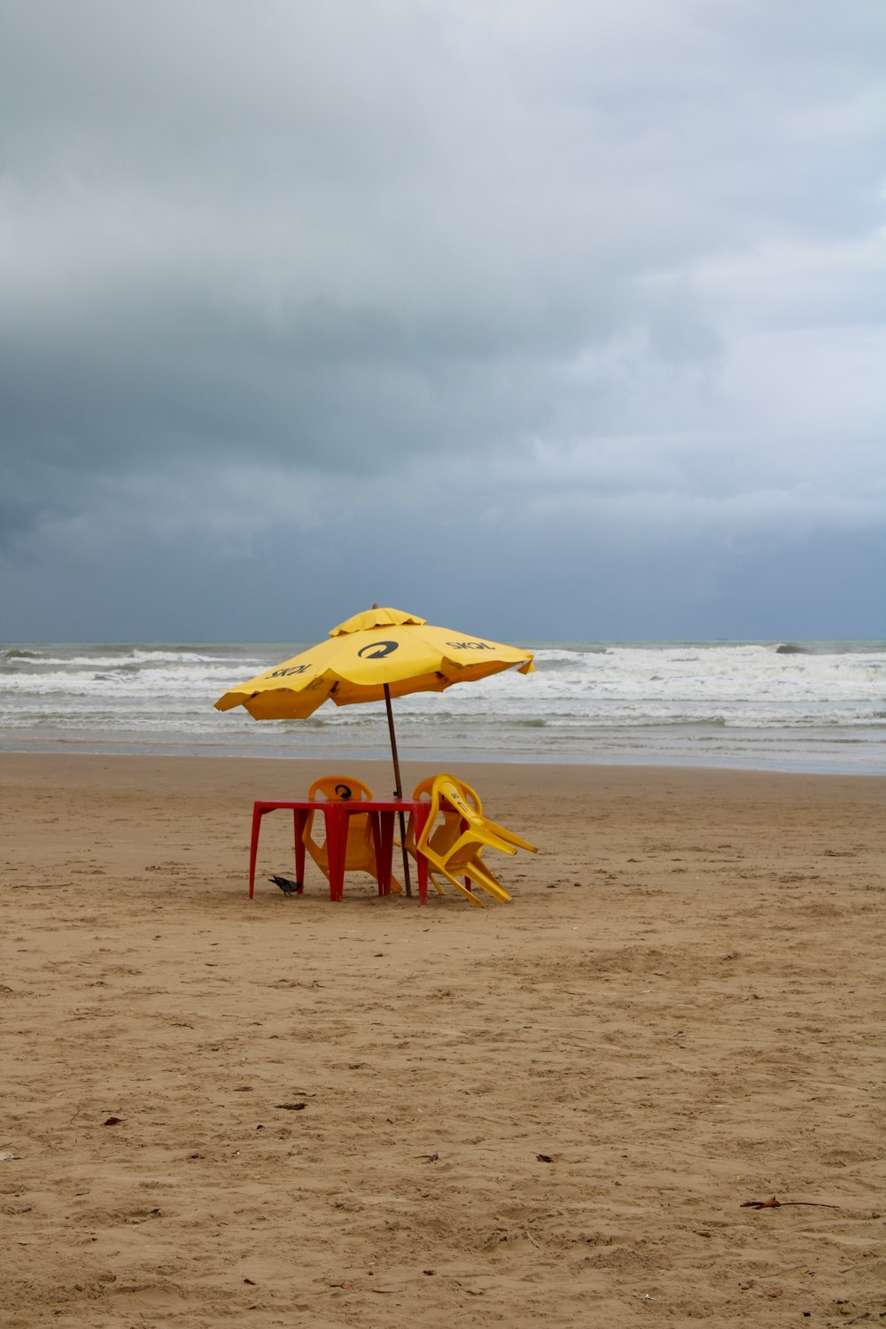 a yellow umbrella sitting on top of a sandy beach