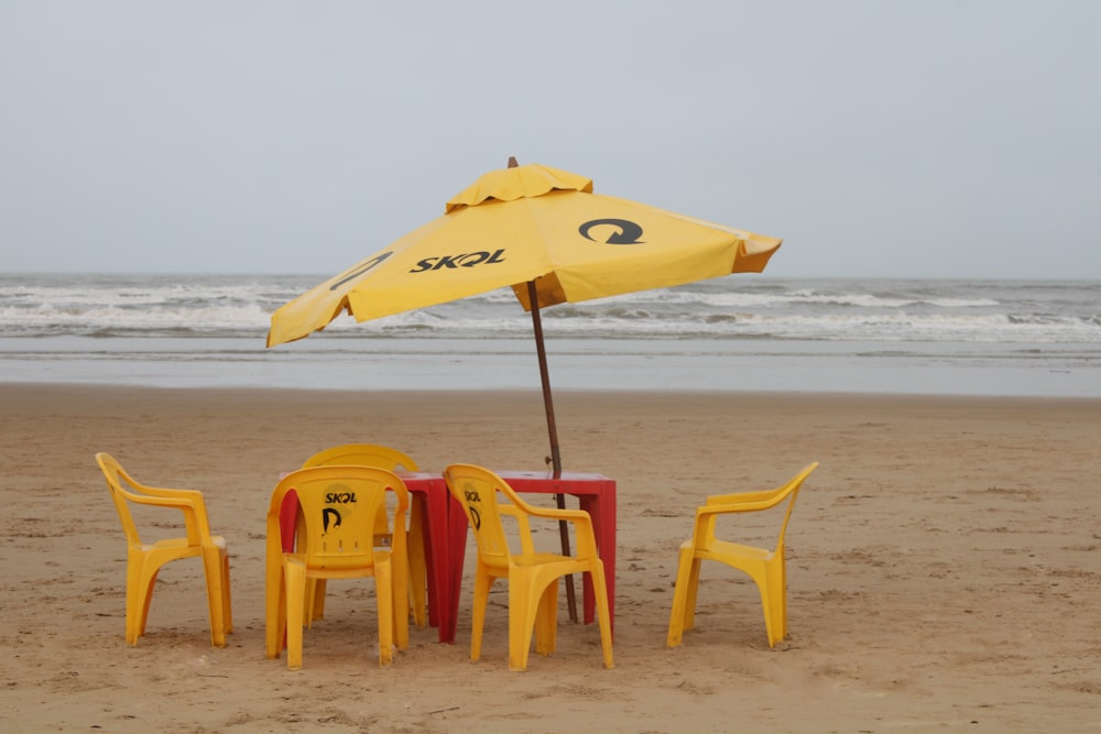a yellow umbrella and some chairs on a beach