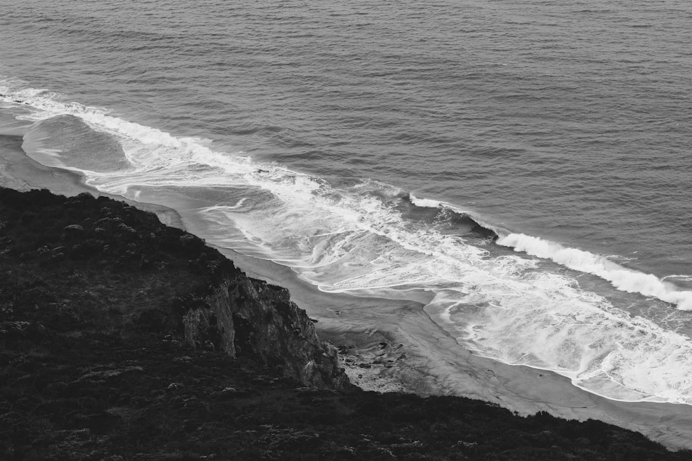 a black and white photo of the ocean and a cliff