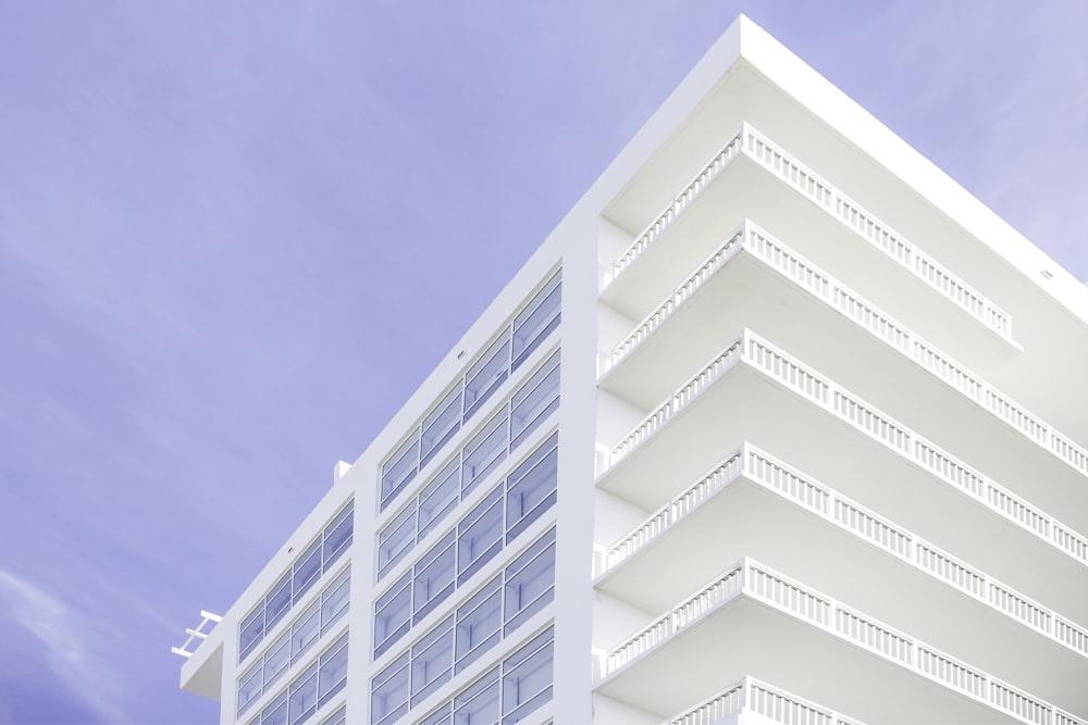 a tall white building with balconies on top