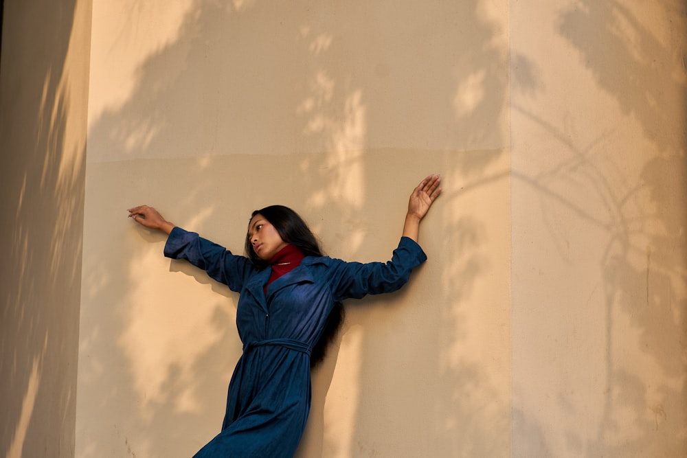 a woman leaning against a wall with her arms outstretched