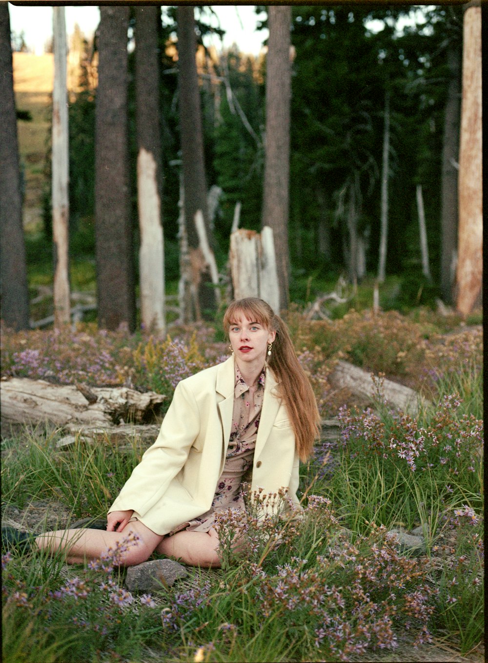 a woman is sitting in a field of flowers