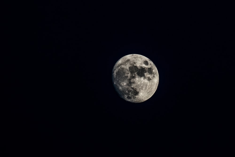 a full moon is seen in the dark sky