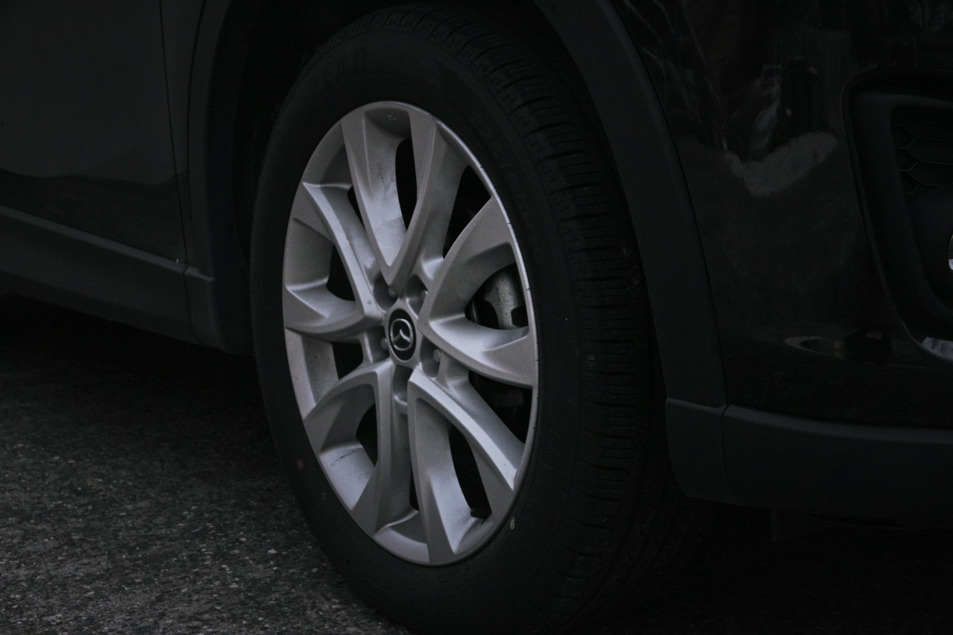 A close-up shot of a shiny SUV tyre mounted on a sleek alloy wheel, highlighting the deep tread pattern and brand logo.