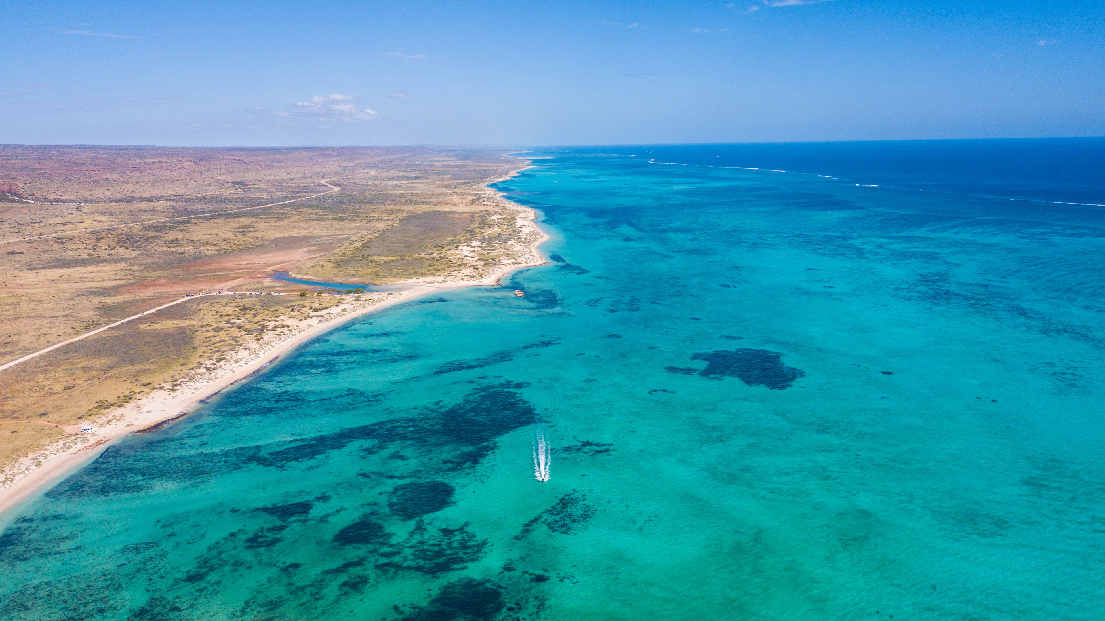 The Ningaloo coast from the air: a turquoise lagoon, patches of reef and dry coastal plain