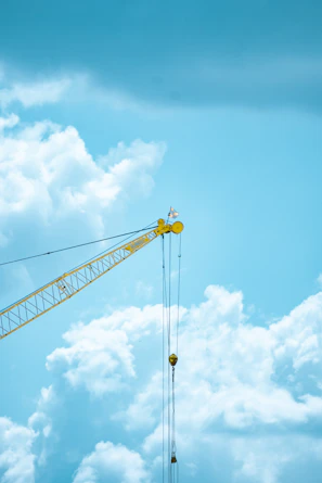 A cheerful crane lifting materials against a clear blue sky with vivid yellow accents.