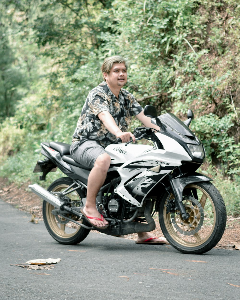 a man riding on the back of a motorcycle down a road