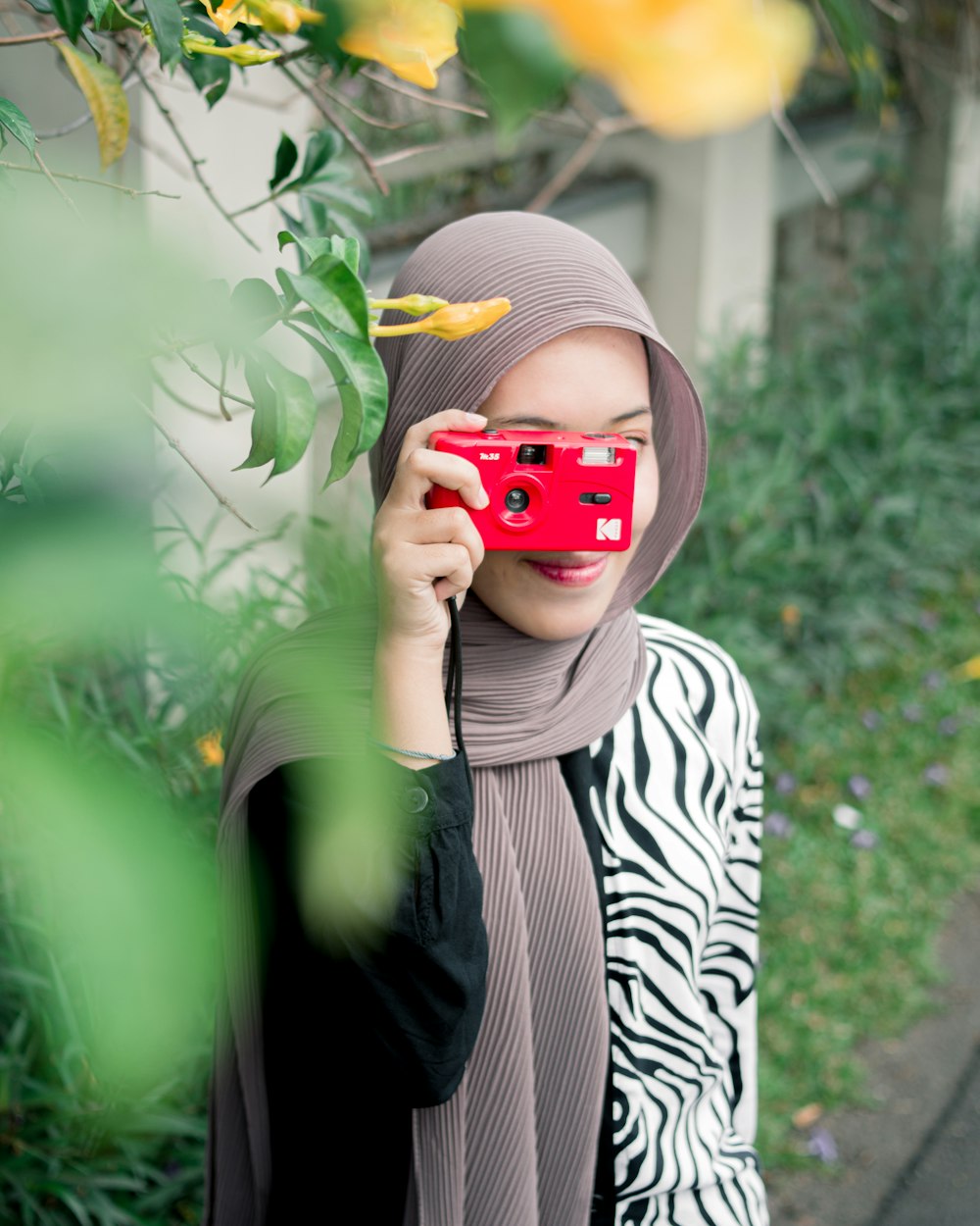 a woman in a hijab holding a red camera