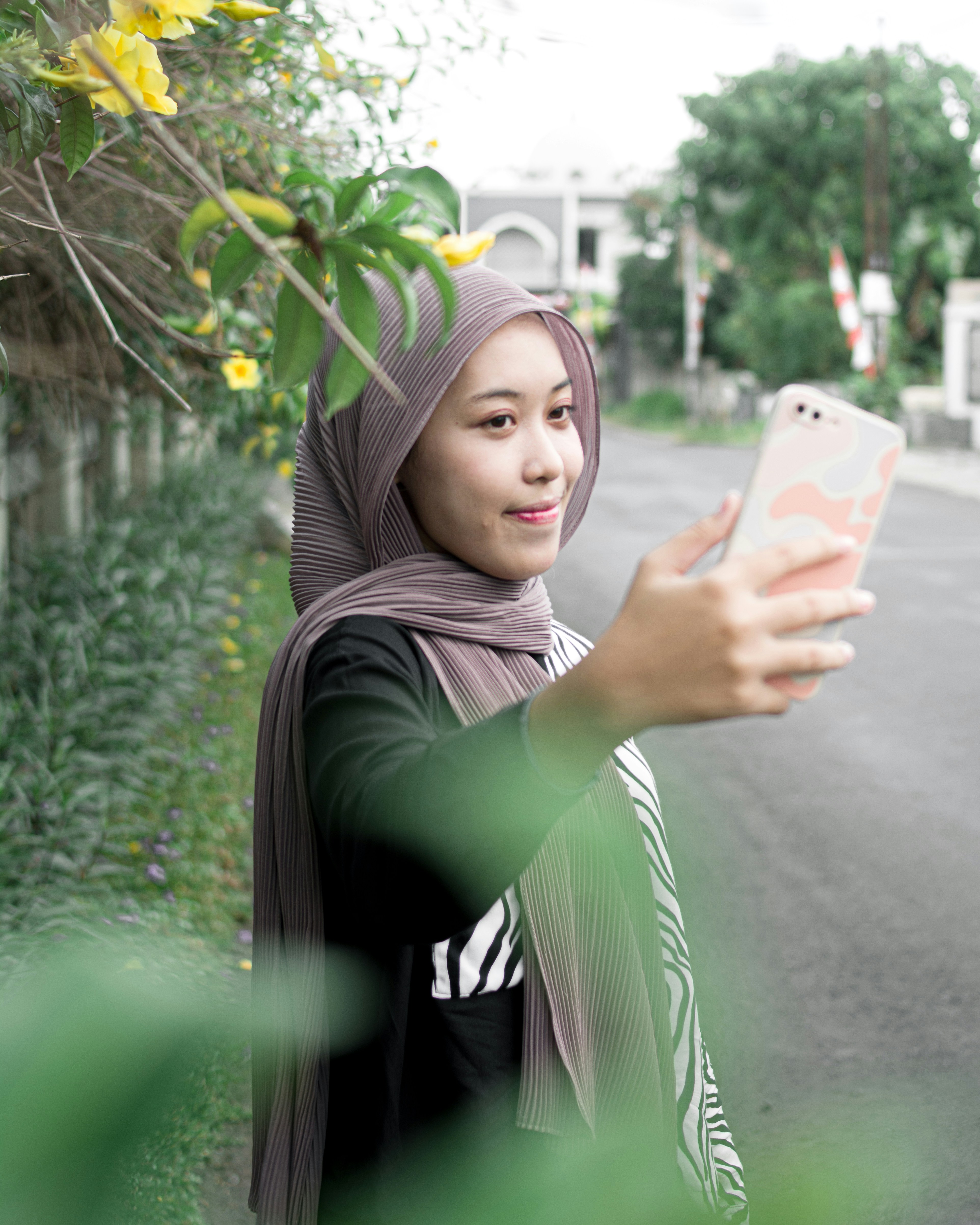Seorang wanita berjilbab mengambil gambar dengan ponselnya