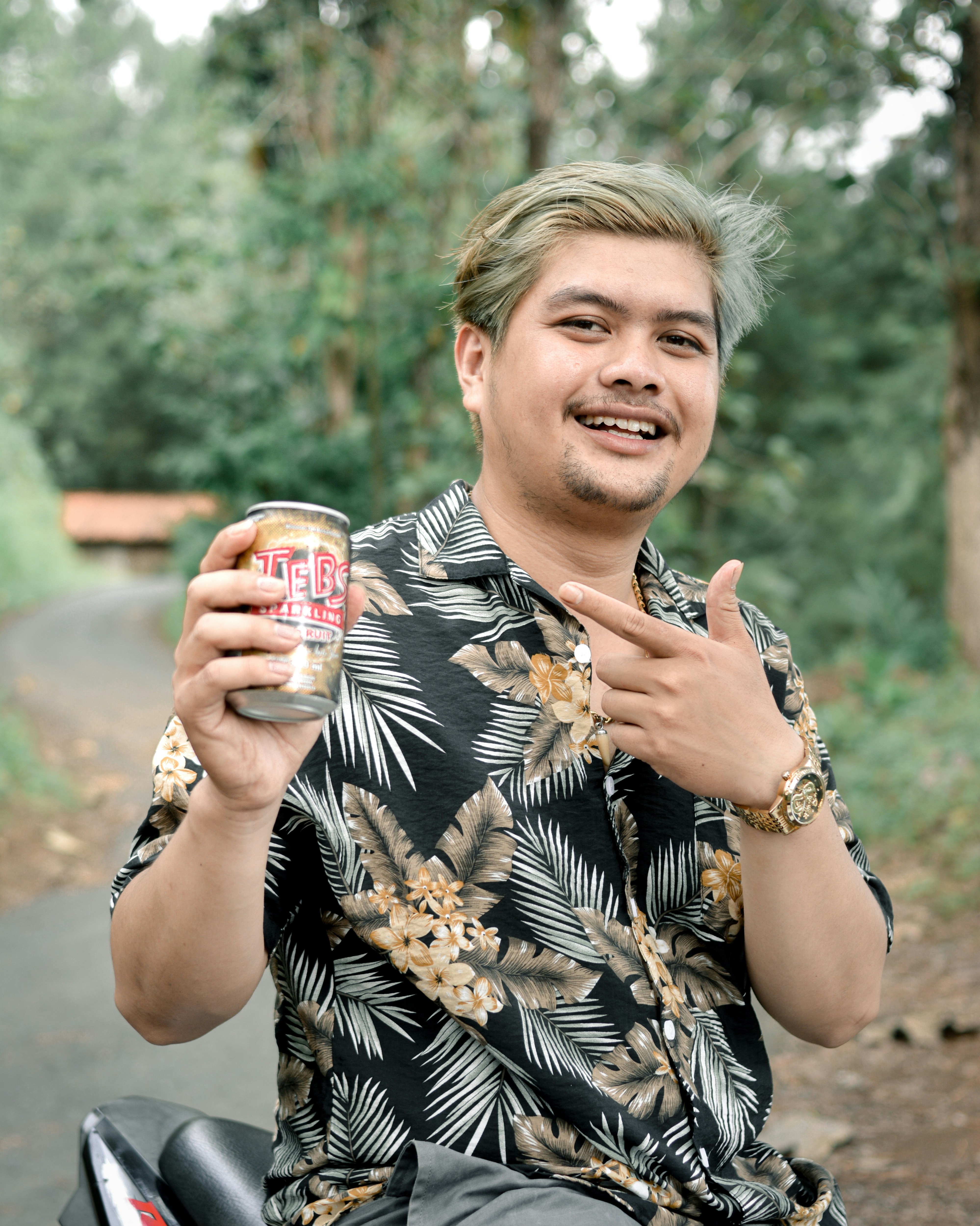 Seorang pria duduk di sepeda motor sambil memegang sekaleng bir