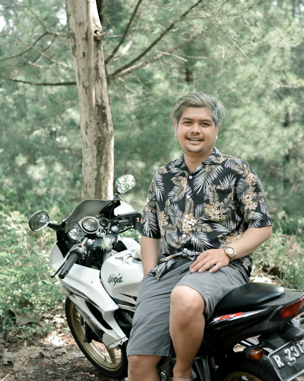 a man sitting on a motorcycle in the woods