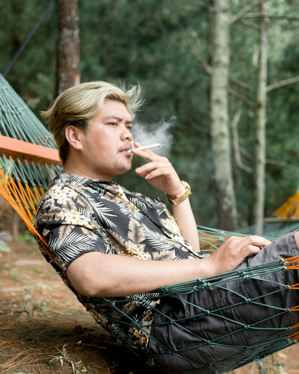 a man sitting in a hammock smoking a cigarette