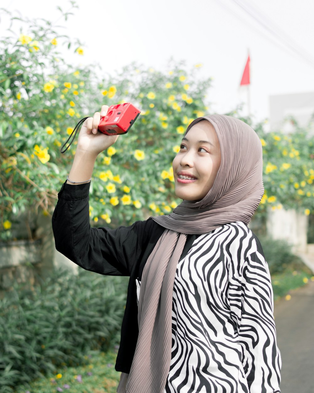 a woman in a hijab taking a picture with her cell phone