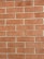 A pattern of uniformly arranged red bricks with beige mortar in between. Each brick has a slightly rough texture, and the wall is well-maintained without any noticeable cracks or damage.