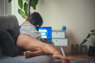 a woman laying on a couch using a laptop