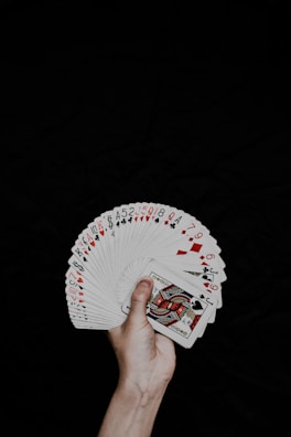 A fan holding a set of glossy photocards spread out in their hand.