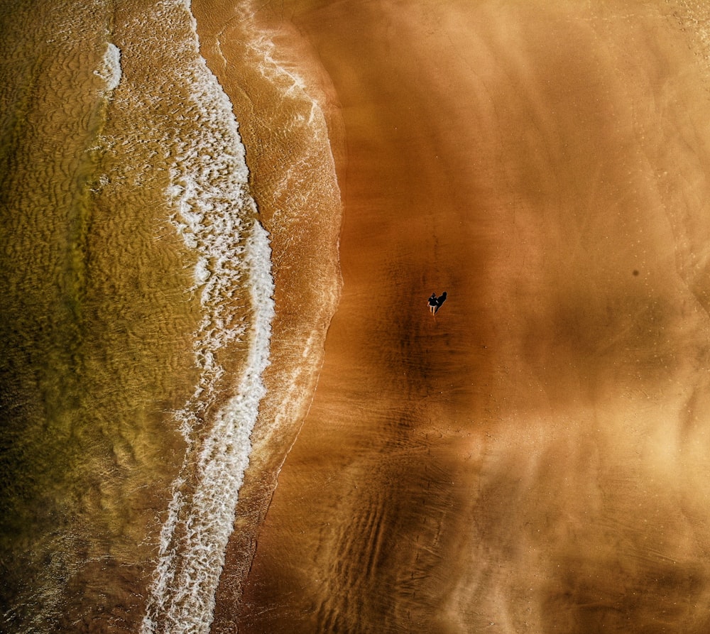 una vista aerea di una spiaggia con una persona che cammina nell'acqua