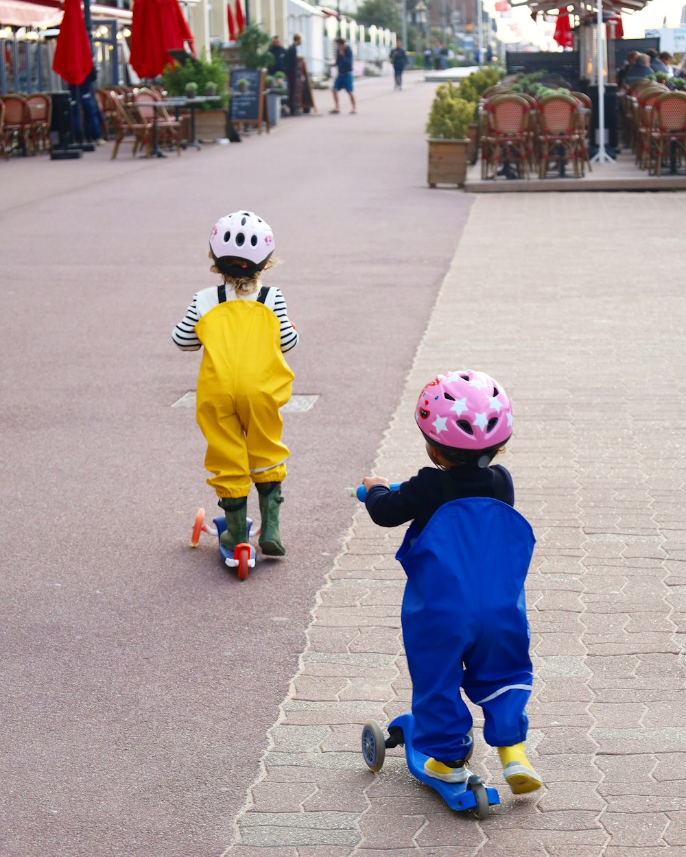 Un par de niños montando patinetas por una acera