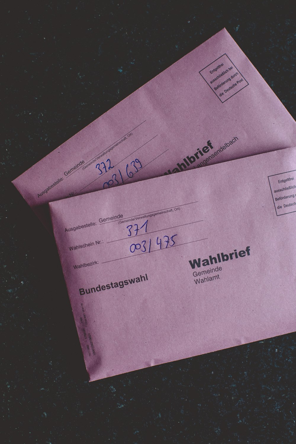 two pink envelopes sitting on top of a table